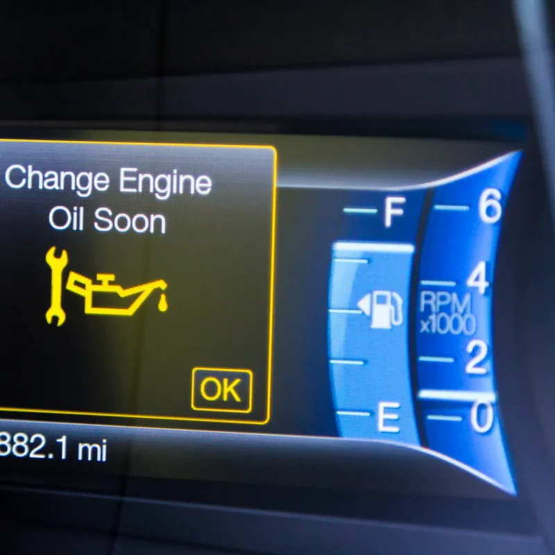 A car dashboard display showing a yellow "Change Engine Oil Soon" warning with a wrench and oil can icon, next to the fuel gauge, tachometer, and an odometer reading 71,882.1 miles.