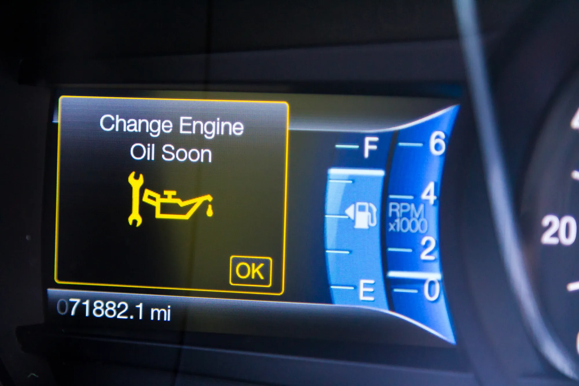 A car dashboard display showing a yellow "Change Engine Oil Soon" warning with a wrench and oil can icon, next to the fuel gauge, tachometer, and an odometer reading 71,882.1 miles.